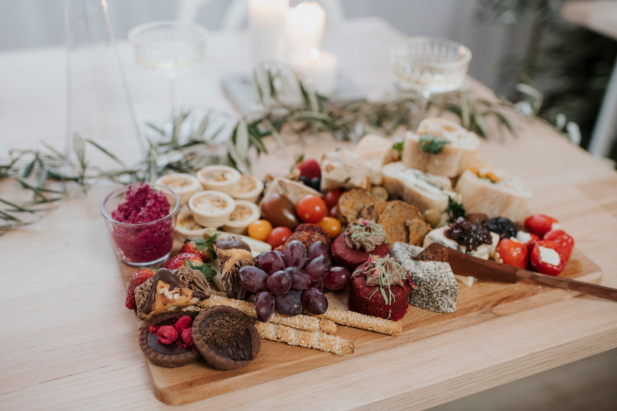 Wooden charcuterie board with various foods on a light background