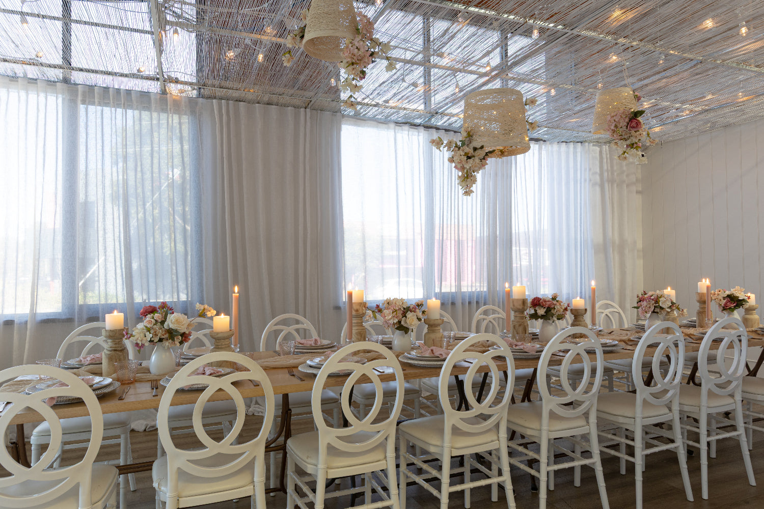 Elegant dining setup with white chairs and tables in a well-lit room.